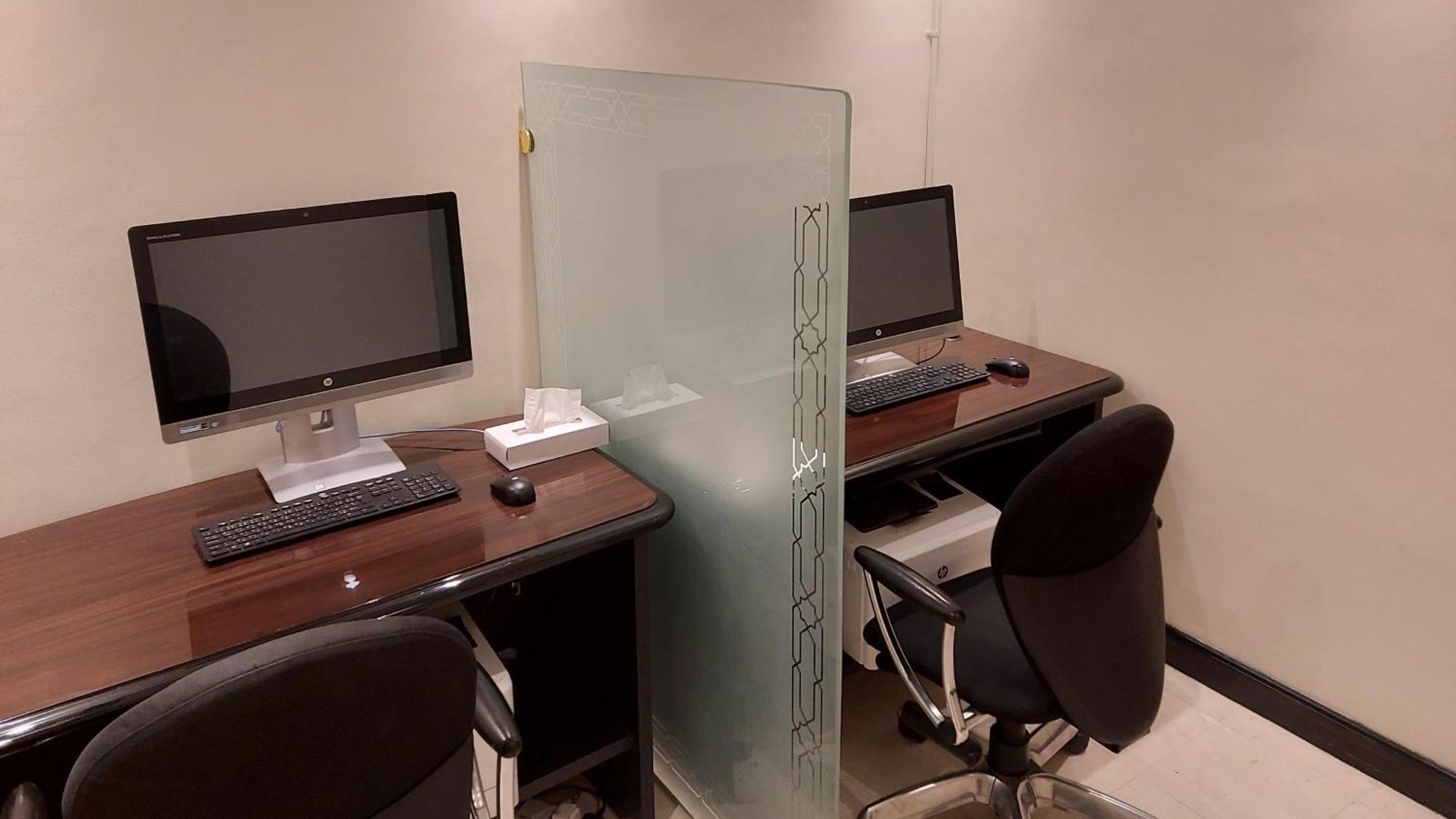 Hotel Intercontinental Dar Al Iman Madinah By Ihg Medina Esterno foto The photo shows a small workspace or office area with two computer desks. Each desk is equipped with a monitor, keyboard, and mouse. A frosted glass partition separates the two workstations, providing some level of privacy. The chairs are ergonomic a