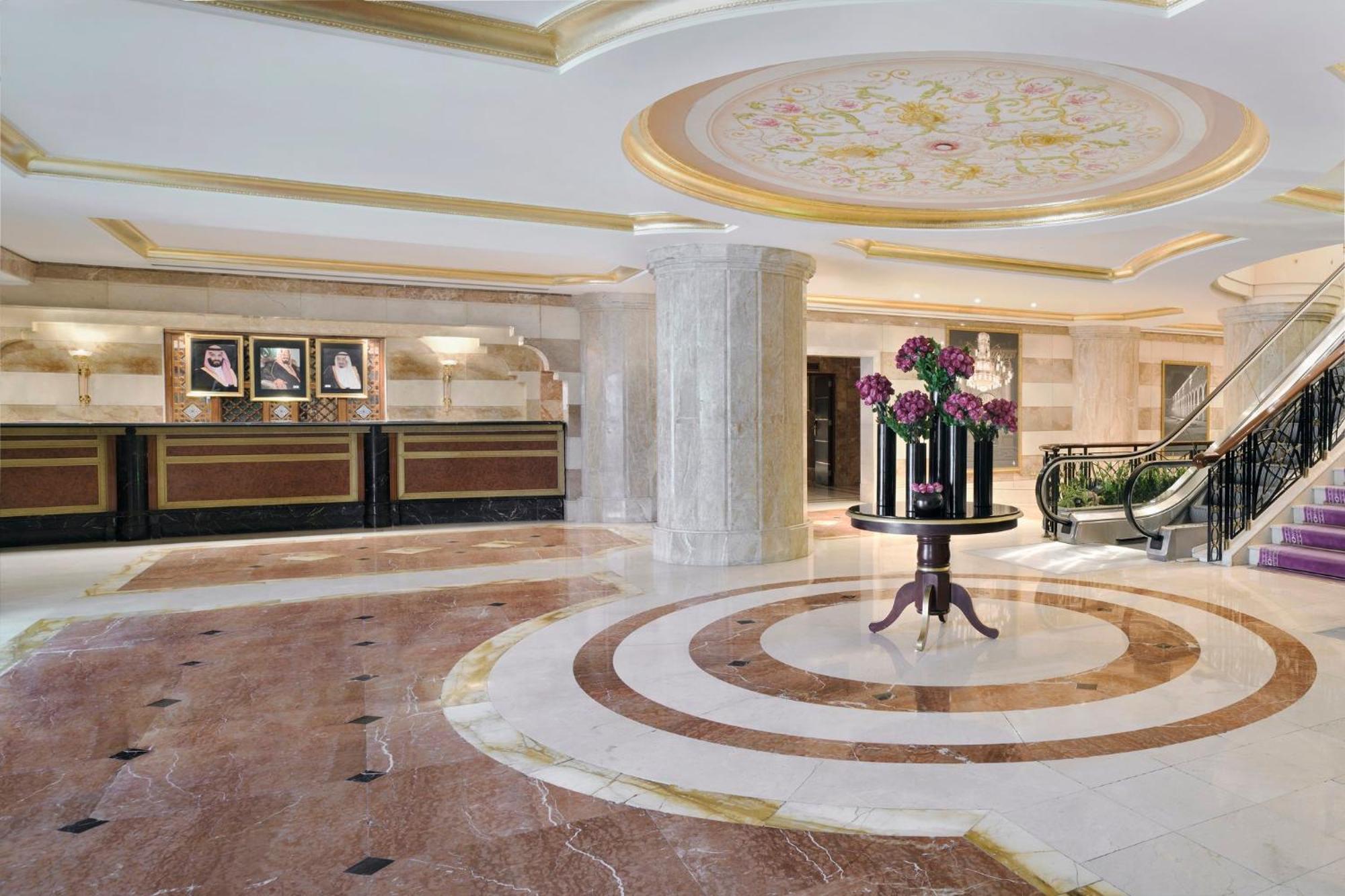 Hotel Intercontinental Dar Al Iman Madinah By Ihg Medina Esterno foto The photo shows a luxurious hotel lobby. The space features elegant marble flooring with circular designs, complemented by a large, decorative ceiling. In the center, there is a round table adorned with a floral arrangement. Behind the table, a recep
