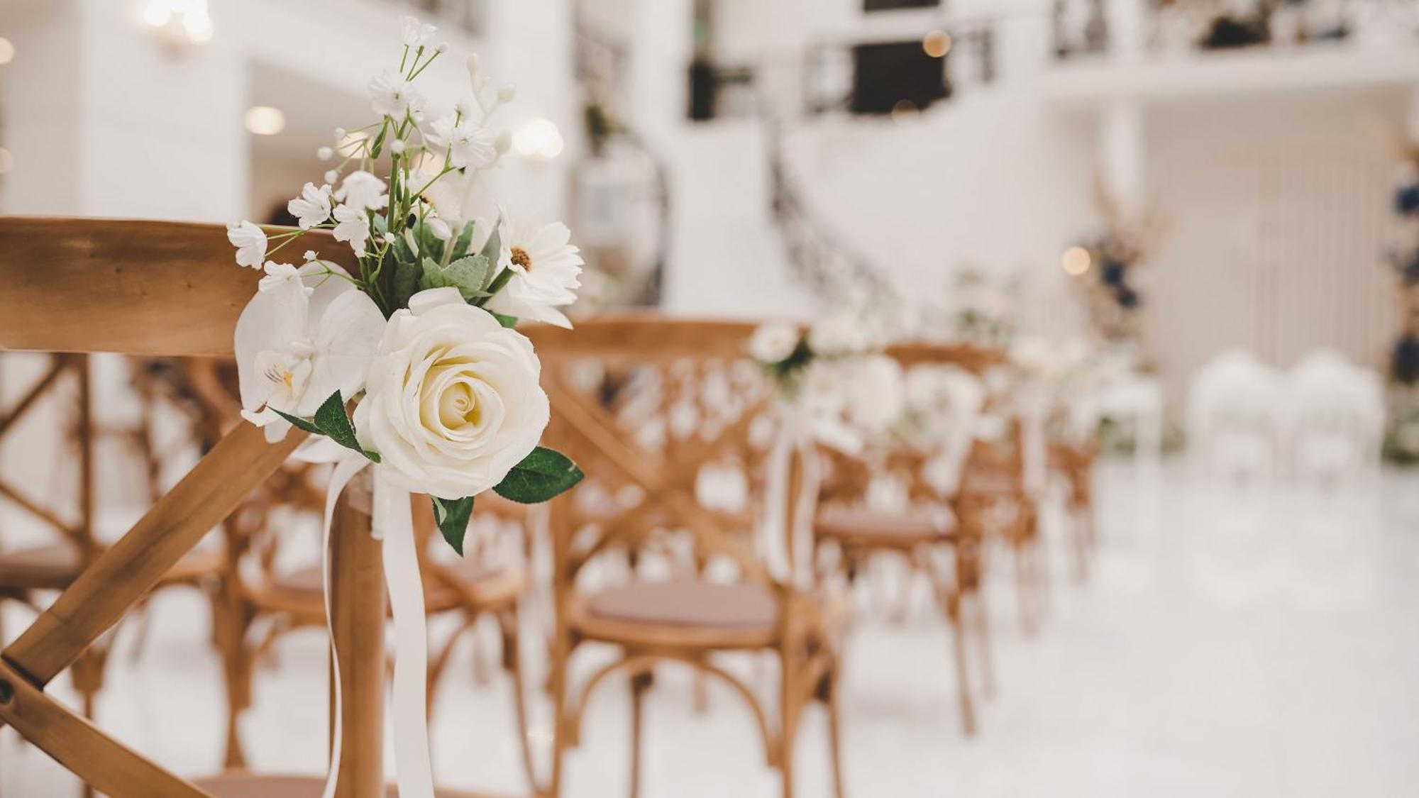 Hotel Intercontinental Dar Al Iman Madinah By Ihg Medina Esterno foto The photo showcases a beautifully arranged event space, likely set up for a wedding or special occasion. In the foreground, wooden chairs are neatly lined up, some adorned with decorative floral arrangements. The flowers include white roses and small