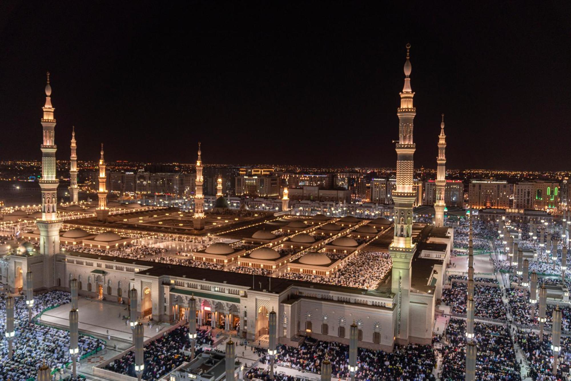 Hotel Intercontinental Dar Al Iman Madinah By Ihg Medina Esterno foto The photo shows a panoramic view of a large mosque complex illuminated at night. It features tall minarets with lights, a vast courtyard filled with people, and a beautifully lit architectural design. The overall ambiance suggests a significant space