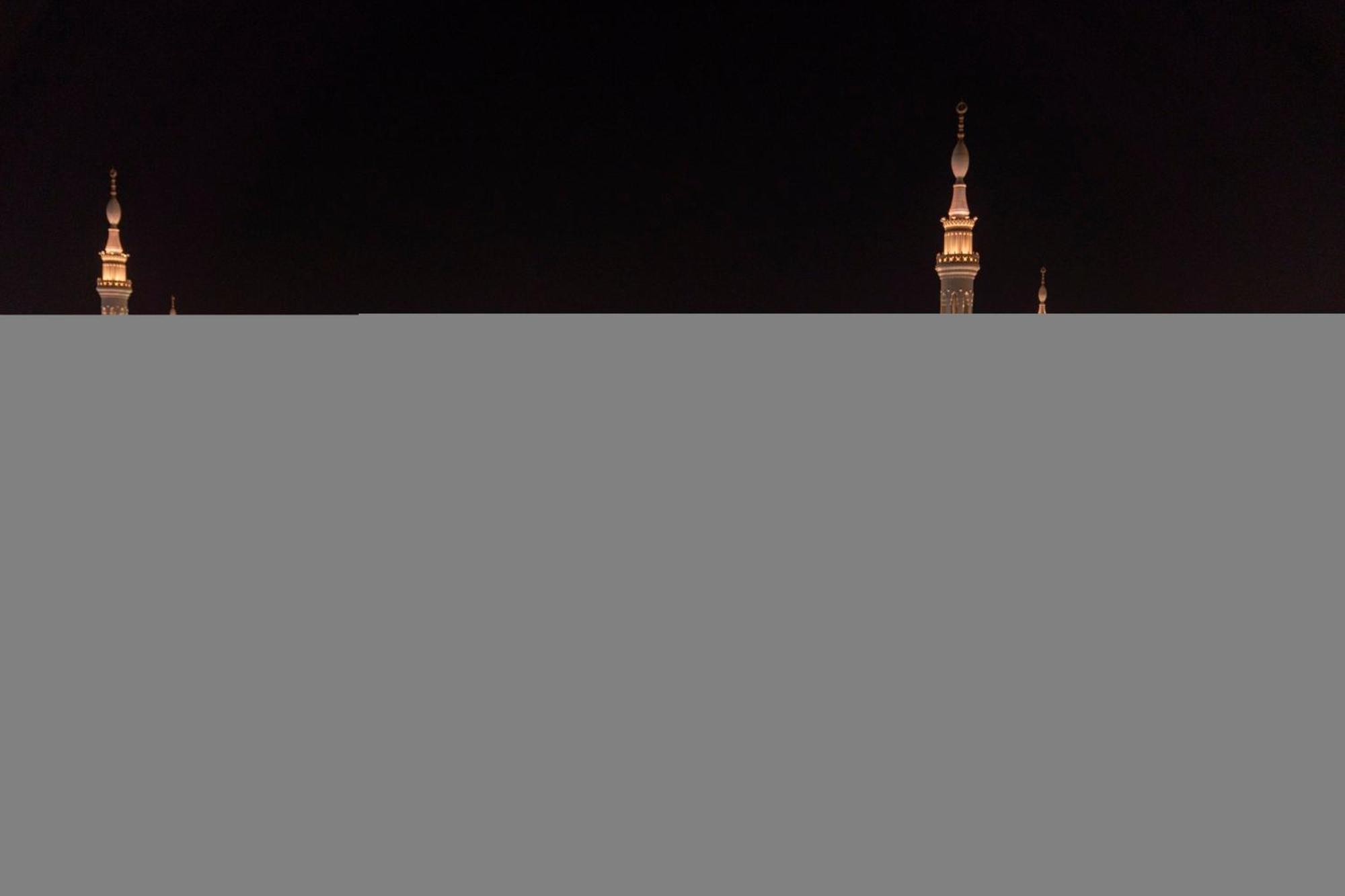 Hotel Intercontinental Dar Al Iman Madinah By Ihg Medina Esterno foto The image appears to show a night scene featuring tall structures with pointed tops, likely minarets, illuminated against a dark background. The lighting creates a striking contrast, highlighting the architectural details of the structures. The overa