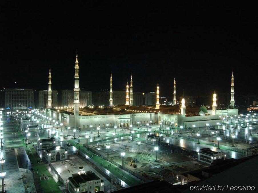 Hotel Intercontinental Dar Al Iman Madinah By Ihg Medina Amenities foto The image shows the illuminated landscape of a mosque complex at night. It features several tall minarets, which are typically part of Islamic architecture, adorned with lights. The mosque's central building is also brightly lit, surrounded by an ope